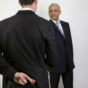 Woodlands private investigator photo of man shaking hands with another and fingers crossed behind back