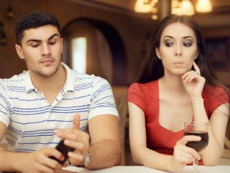 Couple each on their cell phone looking for information about how to know if your spouse is cheating