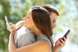 Couple each sending cheater texts while hugging