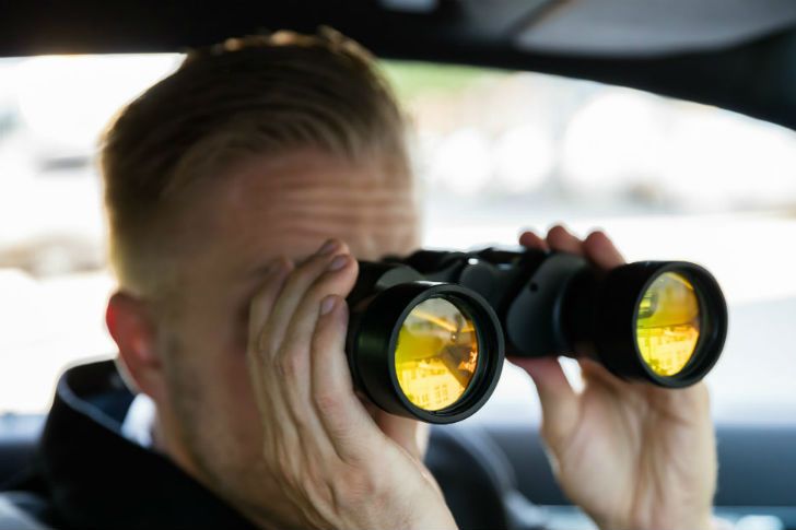 Detective watching for cheater through binoculars